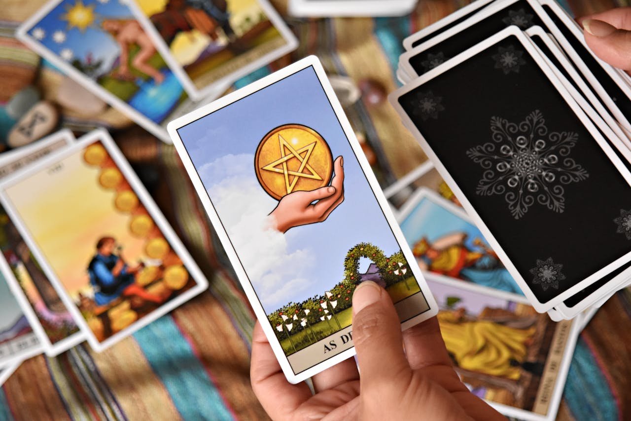 A person holds tarot cards in a colorful setting, showcasing divination tools and symbols.