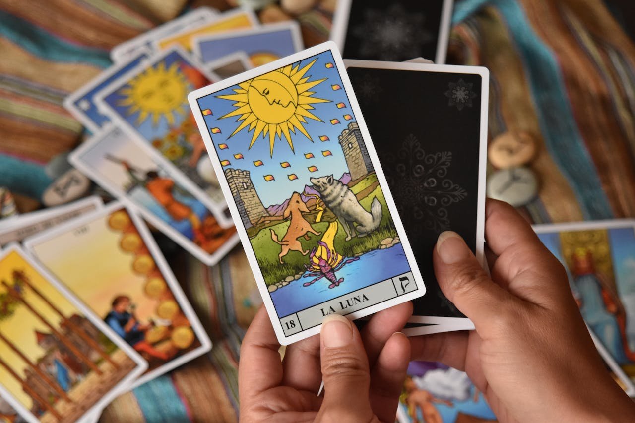 Close-up of hands holding tarot cards featuring 'La Luna', showcasing mystical symbols.